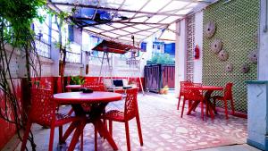 eine Terrasse mit roten Stühlen sowie einem Tisch und Tischen in der Unterkunft Rampriya Service Apartment in Nagpur