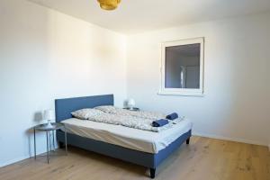 een slaapkamer met een bed met een blauw hoofdeinde en een spiegel bij Vienna Living Apartments - Hadrawagasse in Wenen