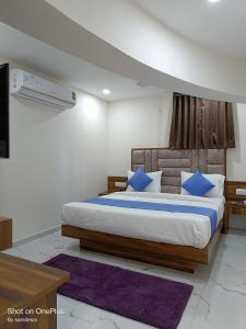 - une chambre avec un grand lit et des oreillers bleus dans l'établissement HOTEL ROYAL GRAND, à Ahmedabad