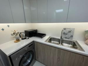 a kitchen with a washing machine and a sink at Lovely New 1 bed Apt - Mirdif Hills Avenue in Dubai