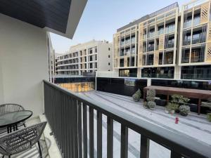 a balcony with a bench and tables and buildings at Lovely New 1 bed Apt - Mirdif Hills Avenue in Dubai