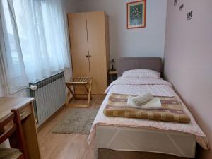 a small bedroom with a bed and a desk at Apartman SAN in Vukovar