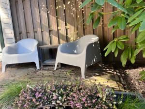 duas cadeiras de plástico sentadas ao lado de uma cerca em Tuinkamer "de Duiventil" aan de rand van de Posbank em Velp