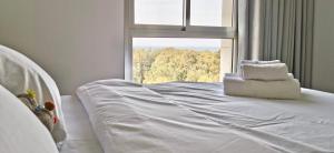 een wit bed in een kamer met een raam bij Sea view apartment with Jacuzzi near beach in Nahariyya