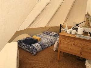 a bed in a tent next to a wooden dresser at Cox Hill Glamping Badger in Truro