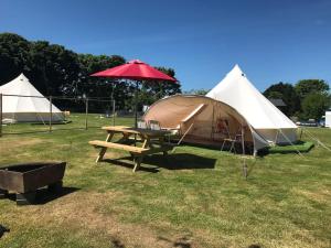 a tent and a picnic table with a red umbrella at Cox Hill Glamping Badger in Truro