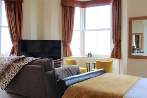 um quarto com um sofá, uma televisão e uma cama em The Crown Hotel em Morecambe