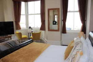 a bedroom with a bed and a television and windows at The Crown Hotel in Morecambe