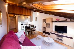 a living room with a purple couch and a kitchen at Apartamentos Cean Bermudez in Gijón