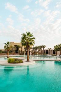 a swimming pool with palm trees in a resort at ERTH Abu Dhabi Hotel in Abu Dhabi