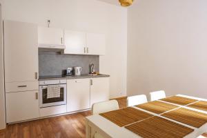 eine Küche mit weißen Schränken und einem Tisch mit Stühlen in der Unterkunft Vienna Living Apartments - Müllnergasse in Wien