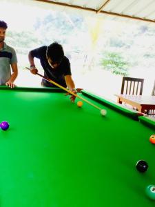 duas pessoas a jogar bilhar numa mesa de bilhar verde em Aita River Resort em Dogadda