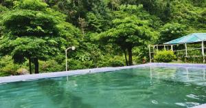 uma piscina vazia com árvores ao fundo em Aita River Resort em Dogadda