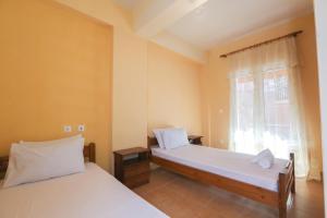 a bedroom with two beds and a window at Platouka's House in Ágios Matthaíos