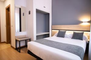 a bedroom with a large white bed and a table at Alda Puerto Seco in Burgos