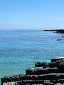 una vista del océano con agua azul y rocas en Visavi' Luxury Room, en Torre a Mare