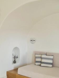 a white bedroom with a bed with two pillows at Ammothines Cycladic Suites in Naxos Chora