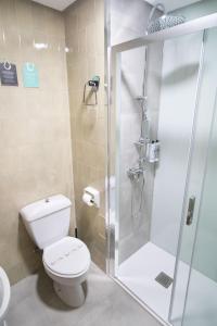 a bathroom with a toilet and a glass shower at Alda Puerto Seco in Burgos