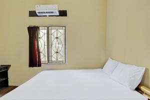 1 dormitorio con cama blanca y ventana en OYO 92197 Zahira Homestay, en Ekas