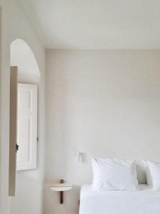 a white bedroom with a bed and a window at Ammothines Cycladic Suites in Naxos Chora