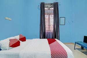 1 dormitorio con 1 cama con almohadas rojas y blancas en OYO 92177 Arafah Homestay Syariah en Bangkinang