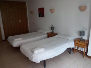 two beds in a room with two night stands and two lamps at Apartaments Els Avets in Pas de la Casa