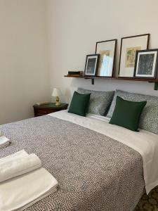1 dormitorio con 1 cama grande con almohadas verdes en Green House Caldiero, en Caldiero