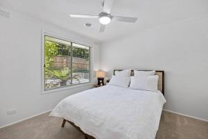 a white bedroom with a bed and a window at 5 min walk to Four Pillars! in Healesville
