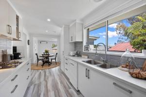 a kitchen with white cabinets and a table and a window at 5 min walk to Four Pillars! in Healesville