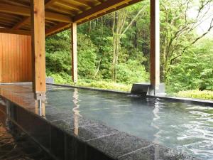 uma piscina de água sob um alpendre com árvores em VIVI熱海 自然郷 3001丨VIVI Atami Shizenkyo 3001 em Atami