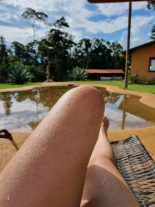 a person laying on a bench next to a swimming pool at Ecovila Coração da Mata in Brumadinho