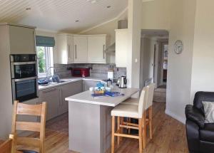 a kitchen with a counter and chairs in a room at Langmere Lakes Lodges in Hainford