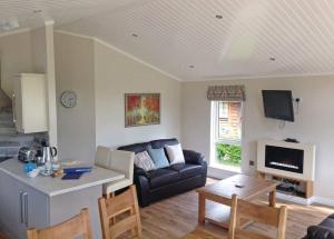 a living room with a couch and a table at Langmere Lakes Lodges in Hainford