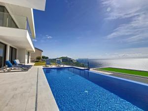 a swimming pool in front of a house with the ocean at Francelho 1 Apartment by LovelyStay in Ribeira Brava