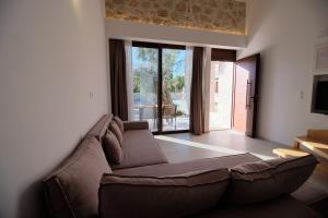 a living room with a brown couch and a large window at Zefiros Luxury Apartments in Sivota