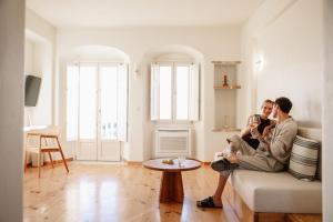 two people sitting on a couch in a living room at Ammothines Cycladic Suites in Naxos Chora