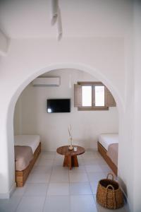 a white room with two beds and a table at Ammothines Cycladic Suites in Naxos Chora