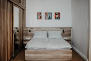 a bedroom with a bed with a wooden headboard at Volenter Lux Apartment Zero in Baja