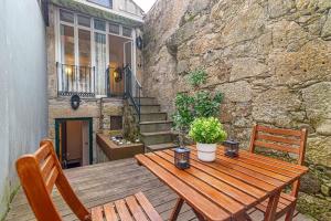 a wooden table and chairs on a patio with a stone wall at Taylors apartment by Innkeeper in Vila Nova de Gaia
