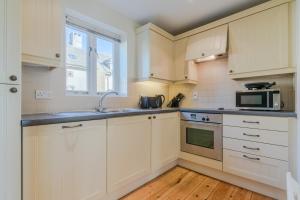 eine Küche mit weißen Schränken und einer Mikrowelle in der Unterkunft Fisherman's Cottage in Somerford Keynes