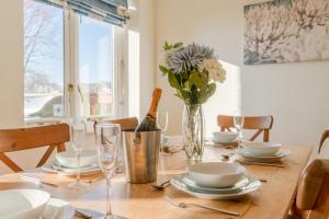 a wooden table with a bottle of wine and a vase of flowers at Fisherman's Cottage in Somerford Keynes +17 photos