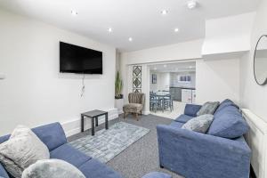 a living room with a blue couch and a tv at Luxury 5 Bedroom Holiday Home Within Prescot in Prescot