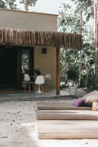 une maison avec un toit de paille, une table et des chaises dans l'établissement CASA SUKHA Hotel, à Trancoso