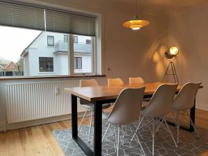 une table à manger avec des chaises et une grande fenêtre dans l'établissement Central lejlighed i Herning, à Herning