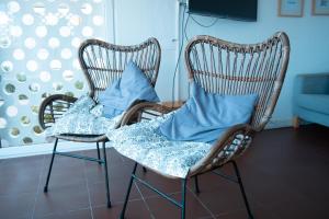 two rocking chairs with blue pillows in a room at Wax Hostel in Faro