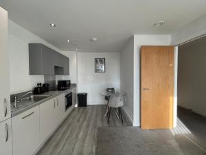 a kitchen with white cabinets and a wooden door at Modern 1 Bedroom Apartment Central Manchester in Manchester