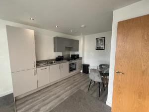 a kitchen with white cabinets and a table at Modern 1 Bedroom Apartment Central Manchester in Manchester