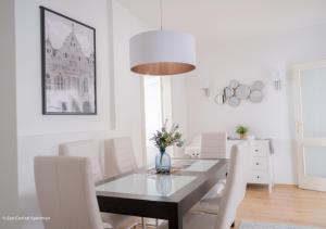 a dining room with a table and white chairs at Central Apartman, Belváros Lakás in Kecskemét
