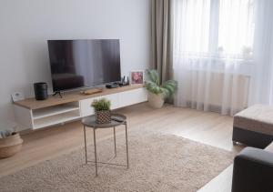 een woonkamer met een flatscreen-tv en een tafel bij Central Apartman, Belváros Lakás in Kecskemét