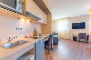 a kitchen with a sink and a living room at Appart’City Confort Montpellier Ovalie I in Montpellier